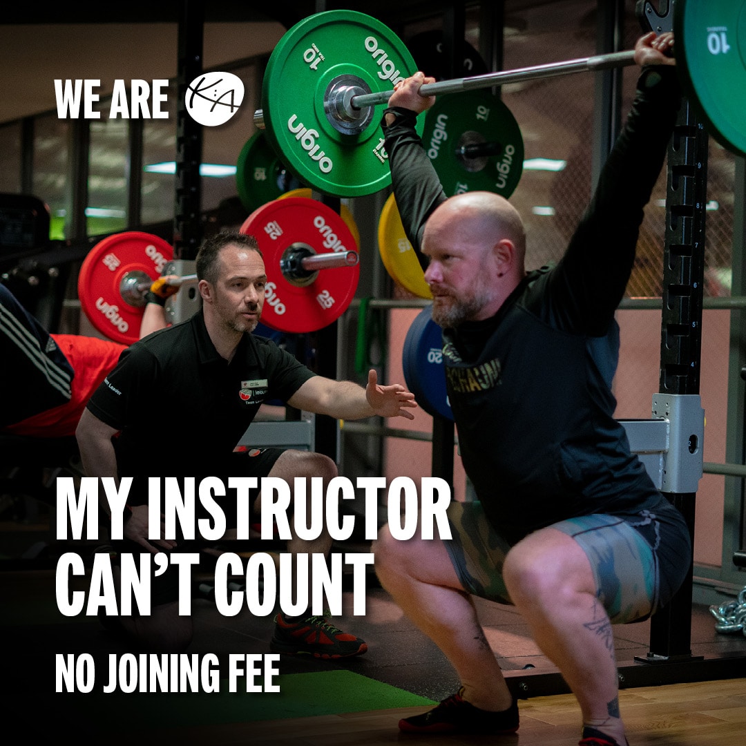 Instructor by the side of a PT client counting the reps of overhead squats